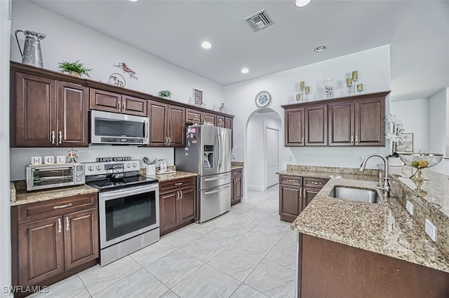 kitchen featuring visible vents, arched walkways, a sink, a toaster, and stainless steel appliances