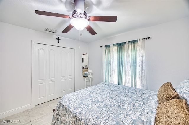 bedroom featuring ceiling fan, visible vents, baseboards, a closet, and light tile patterned flooring