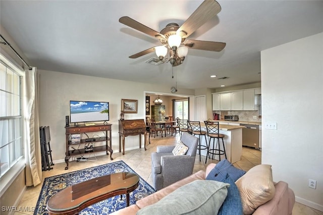 living room featuring light tile patterned floors, baseboards, a ceiling fan, and visible vents