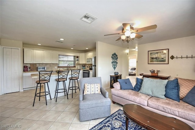 living room with ceiling fan, visible vents, and light tile patterned floors