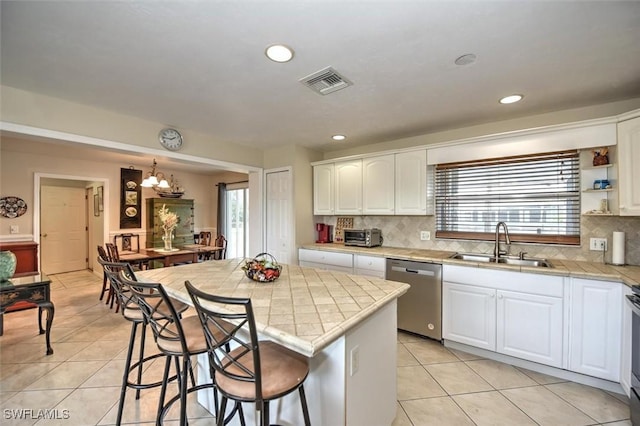 kitchen with visible vents, dishwasher, a sink, light tile patterned floors, and white cabinetry