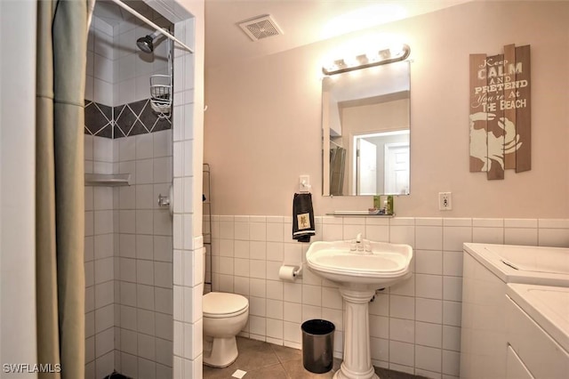 bathroom with visible vents, a stall shower, toilet, and washer and dryer