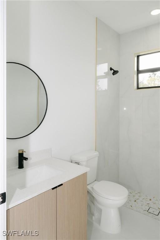 bathroom with vanity, toilet, and tiled shower