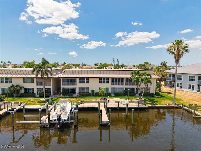 rear view of property with a standing seam roof, boat lift, a water view, and metal roof