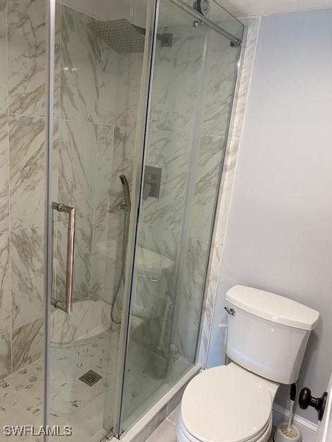 full bathroom with a marble finish shower and toilet