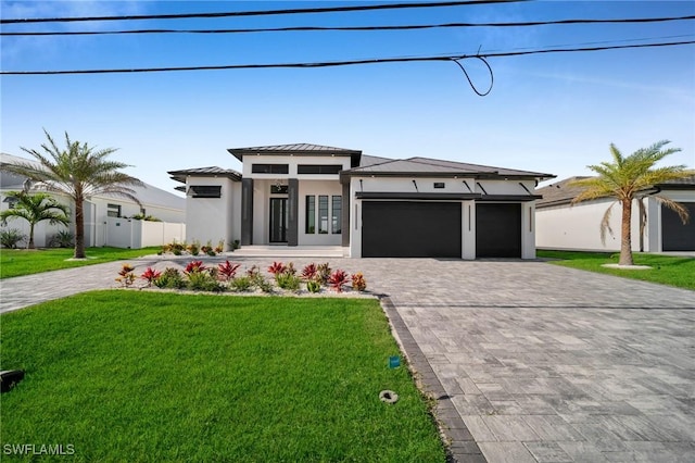 prairie-style house featuring decorative driveway, an attached garage, a front yard, and stucco siding