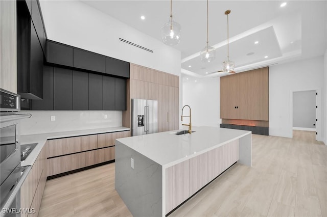 kitchen featuring a sink, light countertops, high end refrigerator, recessed lighting, and modern cabinets