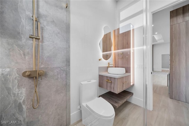 full bath with a marble finish shower, vanity, and toilet