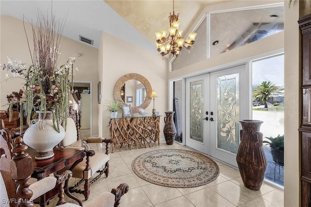 foyer entrance with a chandelier, vaulted ceiling, french doors, and tile patterned floors