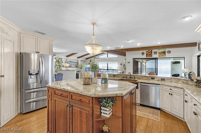 kitchen with stainless steel appliances, light wood-style flooring, light stone countertops, a center island, and a sink