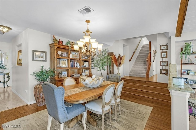 dining area featuring a chandelier, stairs, light wood-style flooring, and baseboards