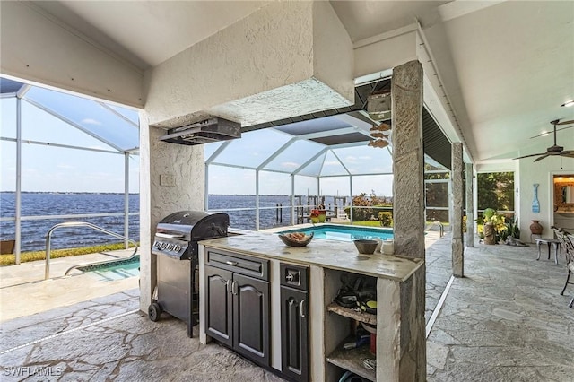 view of patio featuring a water view, a ceiling fan, an outdoor pool, and glass enclosure