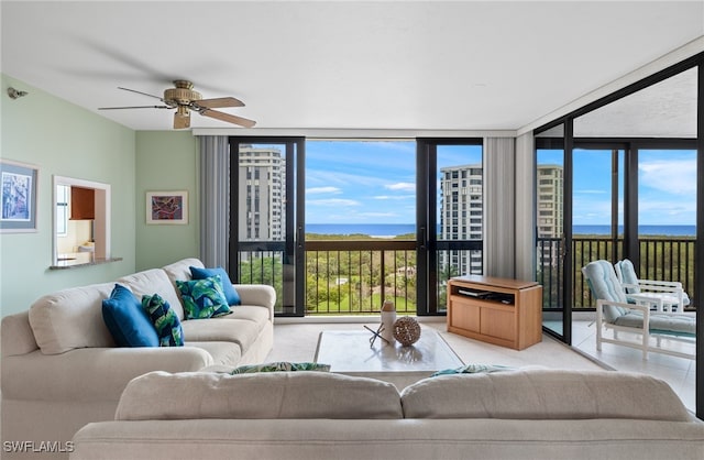 living area featuring a ceiling fan, floor to ceiling windows, and a water view