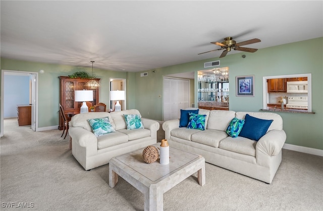 living area with baseboards, ceiling fan, light carpet, and visible vents