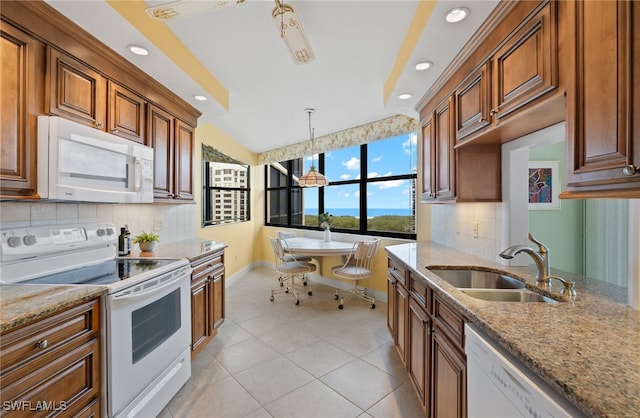 kitchen with light stone countertops, a sink, baseboards, recessed lighting, and white appliances