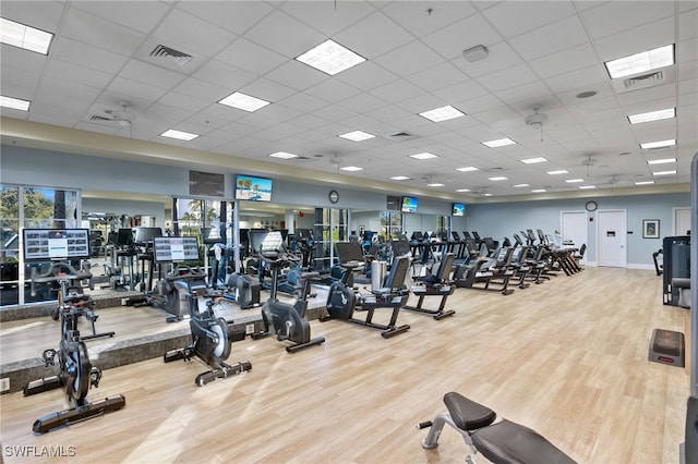 exercise room featuring wood finished floors, a drop ceiling, and visible vents
