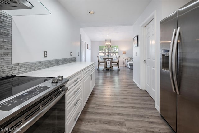 kitchen with an inviting chandelier, electric range, wood finished floors, stainless steel refrigerator with ice dispenser, and white cabinets
