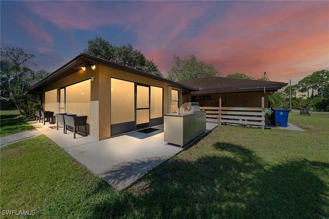 326 Mcarthur Ave, Lehigh Acres, FL 33936 - back of property at dusk with a patio, stucco siding, and a lawn