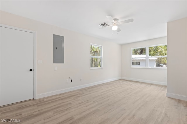 empty room featuring a ceiling fan, visible vents, light wood-type flooring, and electric panel