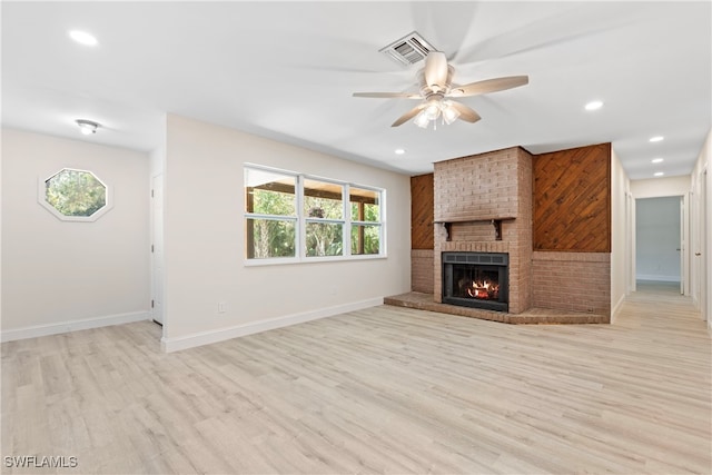 unfurnished living room with a brick fireplace, ceiling fan, baseboards, and light wood finished floors