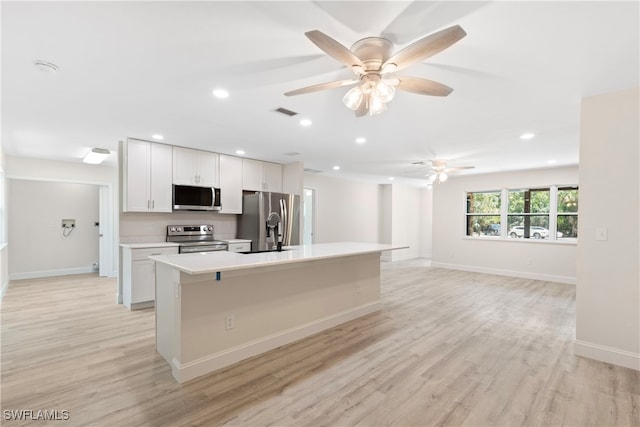 kitchen featuring light countertops, appliances with stainless steel finishes, a center island with sink, and light wood finished floors