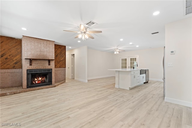 kitchen with baseboards, a brick fireplace, ceiling fan, and visible vents