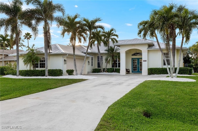 view of front of home featuring an attached garage, a front lawn, stucco siding, french doors, and driveway