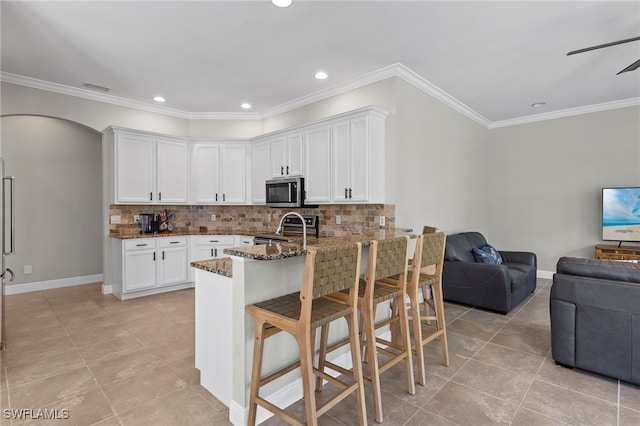 kitchen with appliances with stainless steel finishes, dark stone counters, open floor plan, light tile patterned floors, and backsplash