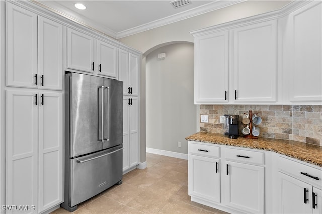 kitchen featuring ornamental molding, baseboards, stone countertops, arched walkways, and high end refrigerator