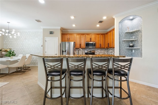 2094 Satsuma Ln, Naples, FL 34120 - kitchen with appliances with stainless steel finishes, dark stone counters, a chandelier, a breakfast bar, and crown molding