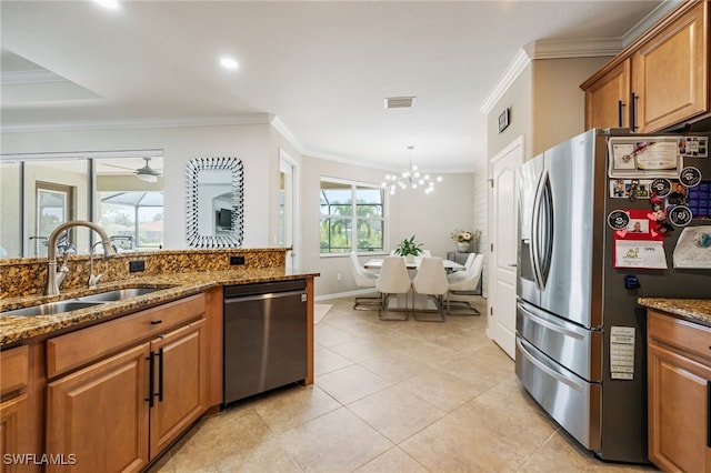 2094 Satsuma Ln, Naples, FL 34120 - kitchen featuring appliances with stainless steel finishes, a sink, brown cabinets, ornamental molding, and dark stone counters