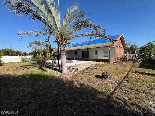 rear view of property with stucco siding, roof mounted solar panels, a fenced backyard, a patio, and a yard