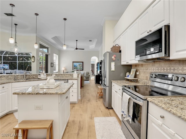 kitchen with a kitchen island, open floor plan, tasteful backsplash, a sink, and appliances with stainless steel finishes