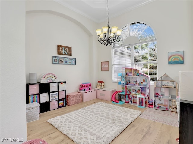 playroom with a notable chandelier, ornamental molding, and wood finished floors