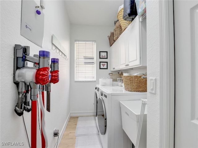 laundry room featuring baseboards, washer and clothes dryer, light wood-style flooring, a sink, and cabinet space