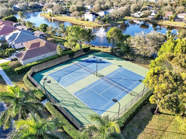 view of sport court with a water view, fence, and a residential view