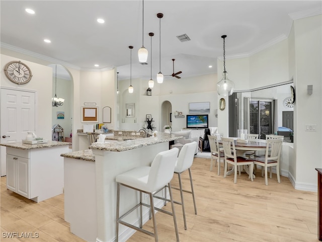 kitchen featuring crown molding, arched walkways, light wood-style flooring, and a spacious island