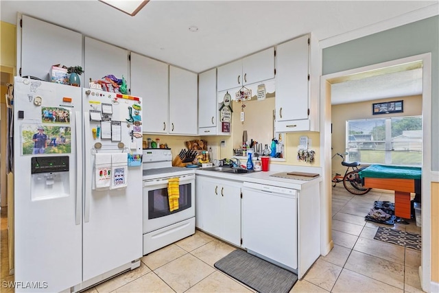 kitchen with a sink, white appliances, light countertops, white cabinetry, and light tile patterned floors