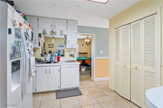 kitchen with a sink, white appliances, light countertops, white cabinetry, and light tile patterned floors