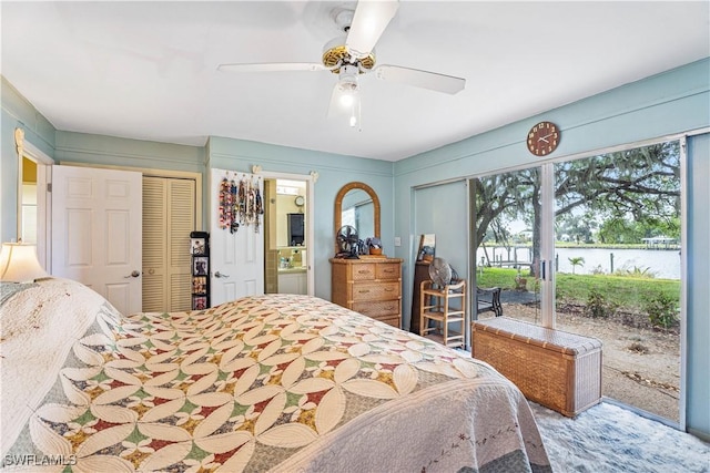 bedroom with a water view, access to outside, ensuite bathroom, and ceiling fan