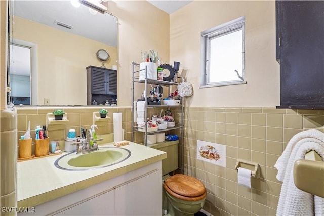 bathroom featuring tile walls, a wainscoted wall, vanity, and visible vents