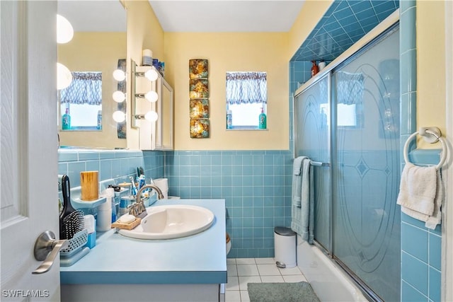 full bathroom with shower / bath combination with glass door, tile patterned flooring, vanity, a wainscoted wall, and tile walls