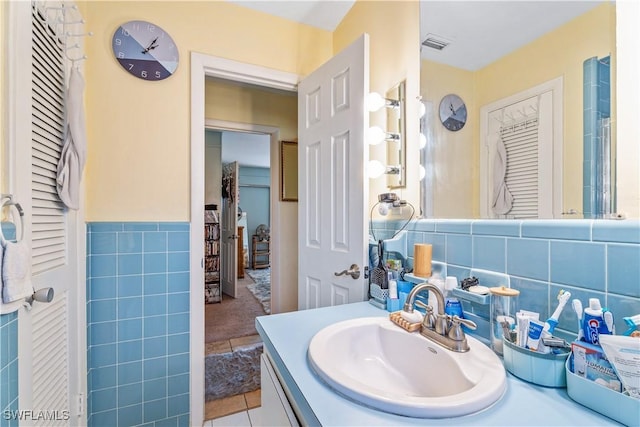 bathroom featuring tile patterned flooring, tile walls, visible vents, and vanity
