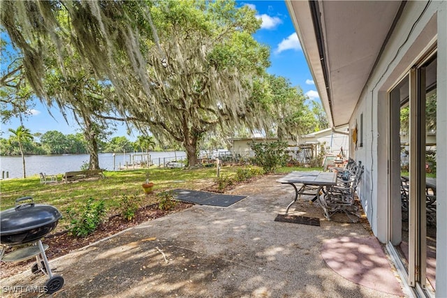 view of patio featuring a water view, fence, and a grill