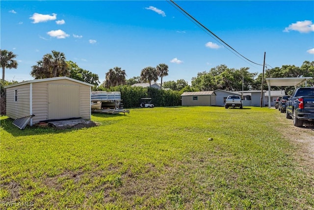 view of yard with a storage unit, an outbuilding, and a carport