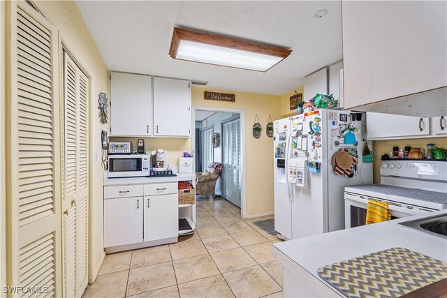 kitchen with light countertops, light tile patterned floors, white cabinets, and white appliances