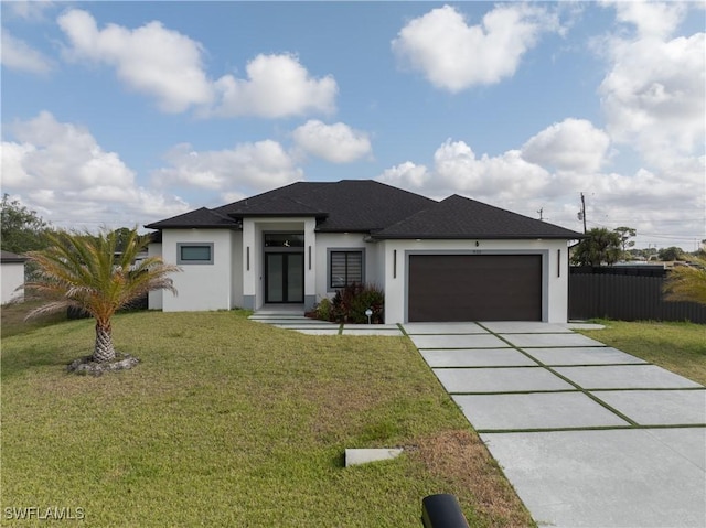 prairie-style house featuring a front yard, fence, concrete driveway, an attached garage, and stucco siding