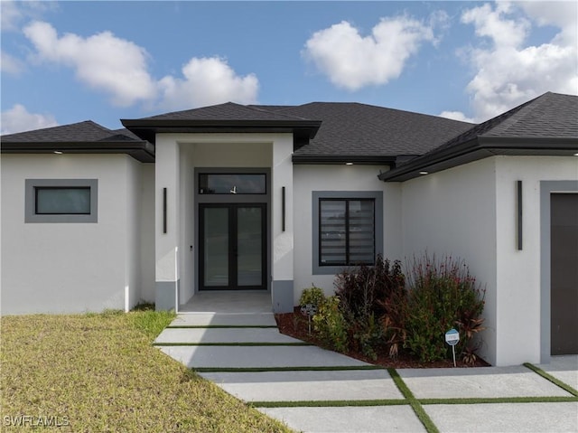 doorway to property with a lawn, a shingled roof, and stucco siding