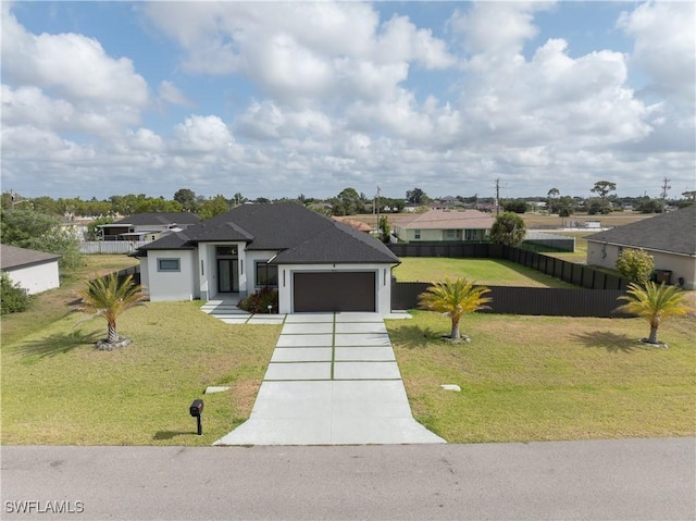 view of front facade with a front yard, a garage, fence, concrete driveway, and stucco siding