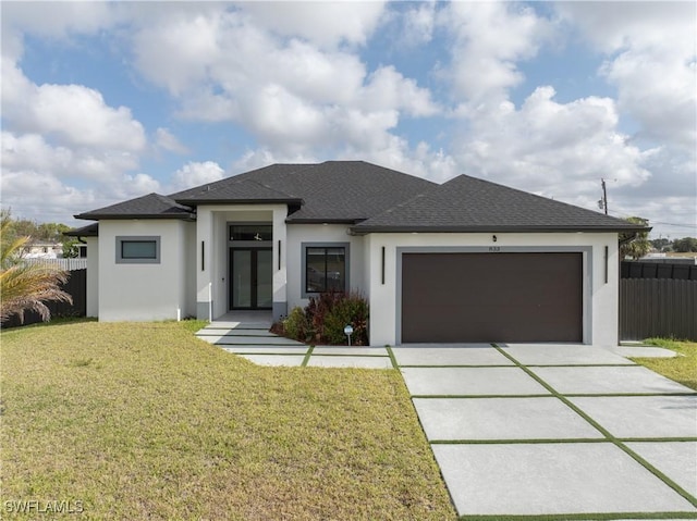 prairie-style house with driveway, fence, a front lawn, an attached garage, and stucco siding
